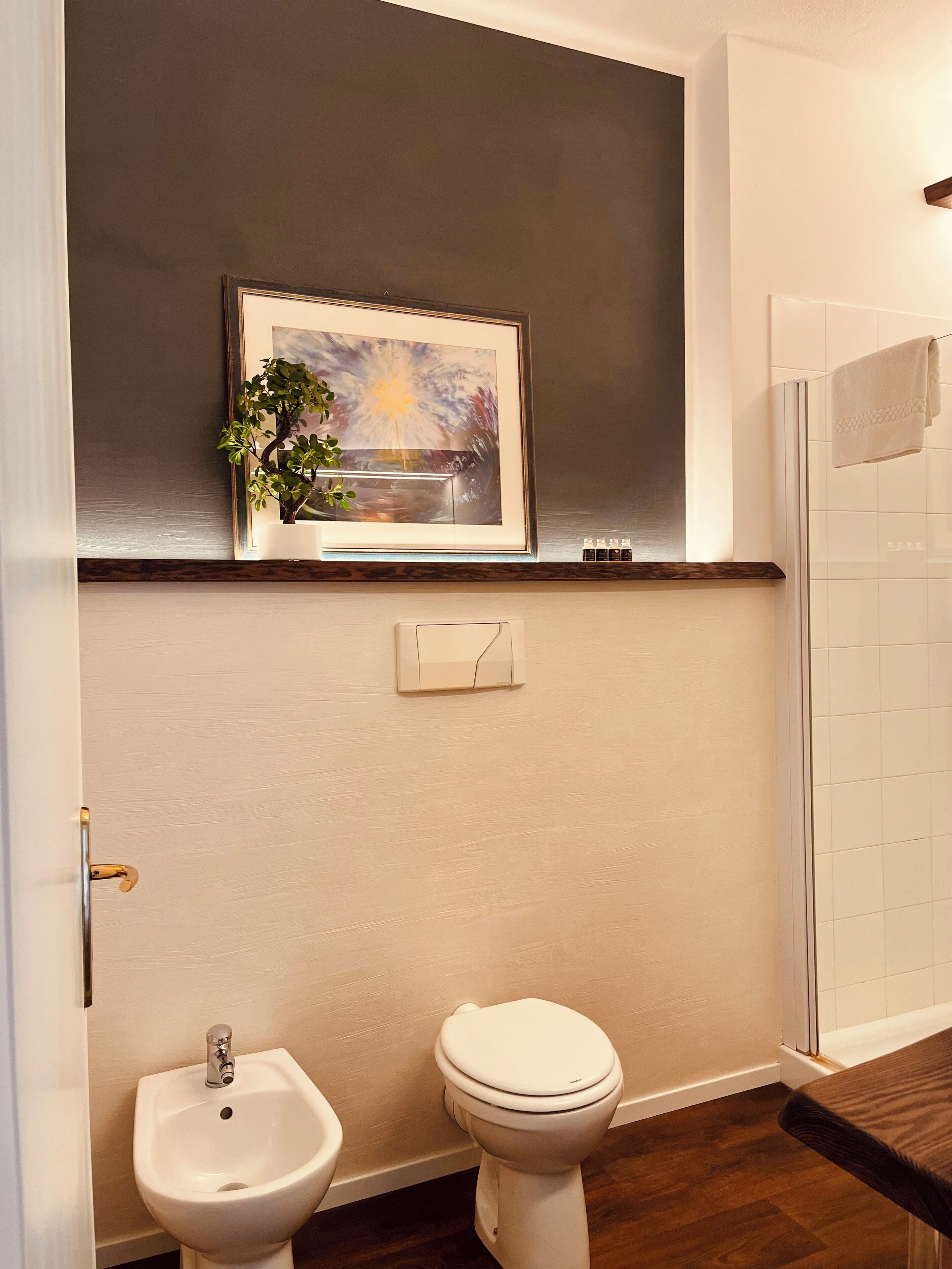 Une salle de bain comprenant des toilettes, un bidet et une œuvre d’art encadrée au-dessus des toilettes.