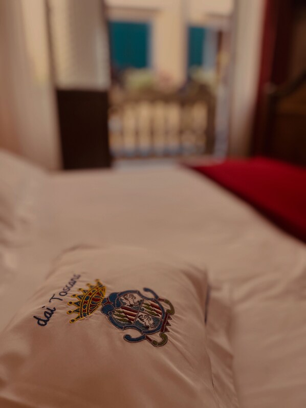 A bed with a white pillow featuring an embroidered coat of arms and the text "dai Tosler." - B&B Dai Toscans (Cividale del Friuli)