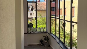 A narrow corridor with large windows, a tiled floor, and potted plants.