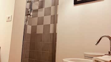 Une salle de bain avec une douche à parois de verre, un lavabo blanc et un tableau encadré au mur.