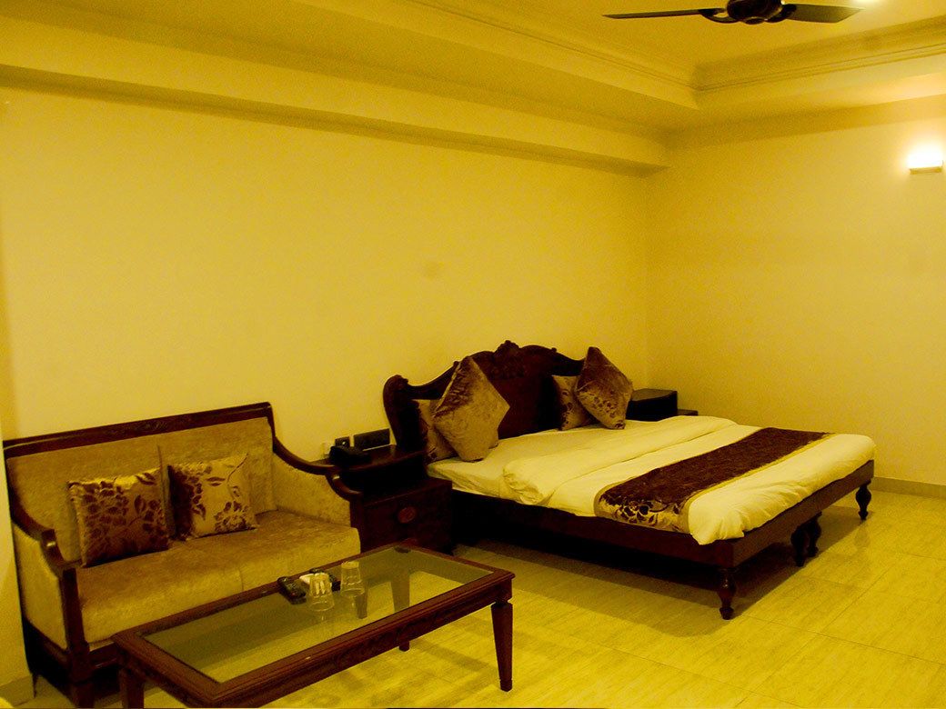 A bedroom with a bed, a sofa, and a glass-top coffee table.