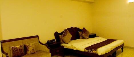 A bedroom with a bed, a sofa, and a glass-top coffee table.