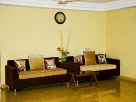 Uma sala de estar com dois sofás, uma mesa de centro e um relógio na parede.