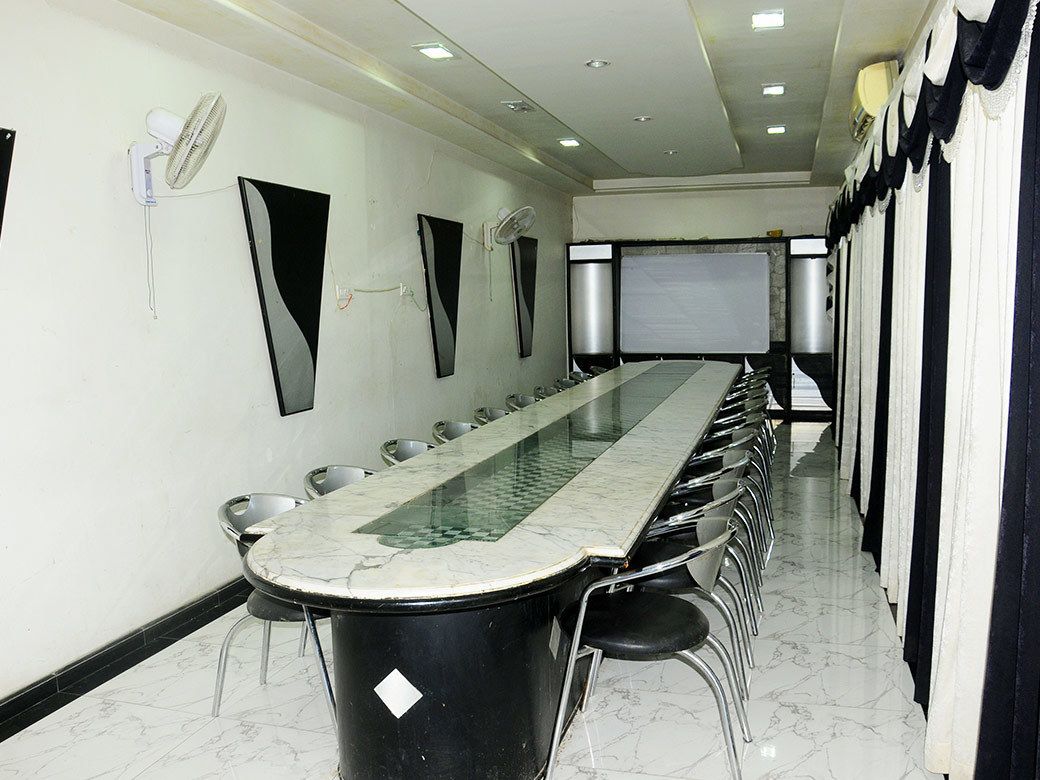 A conference room with a long table, chairs, a projector screen, and a whiteboard.