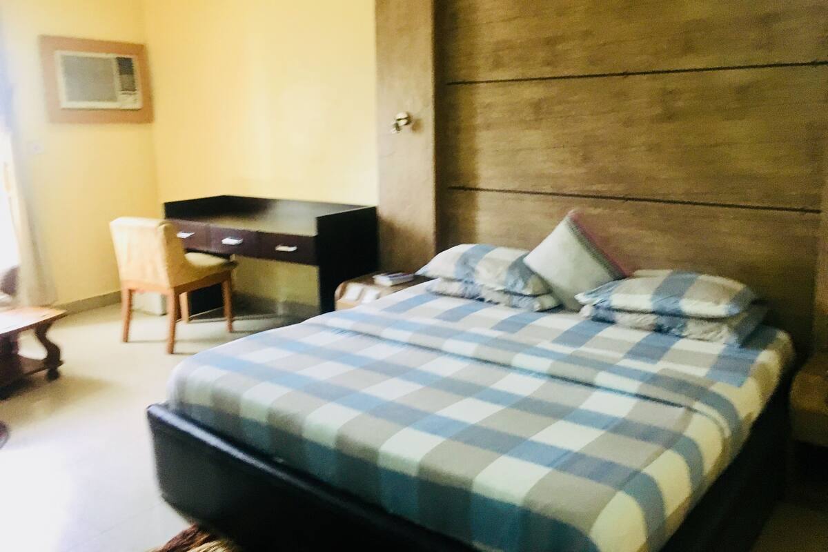 A bedroom with a bed, a desk, and a chair.