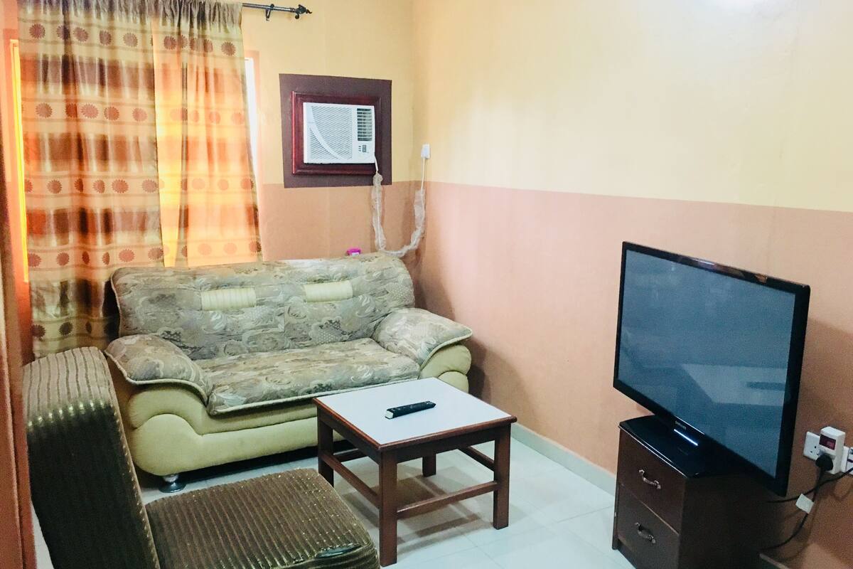 A living room with a sofa, a small table, a television, and a cabinet.