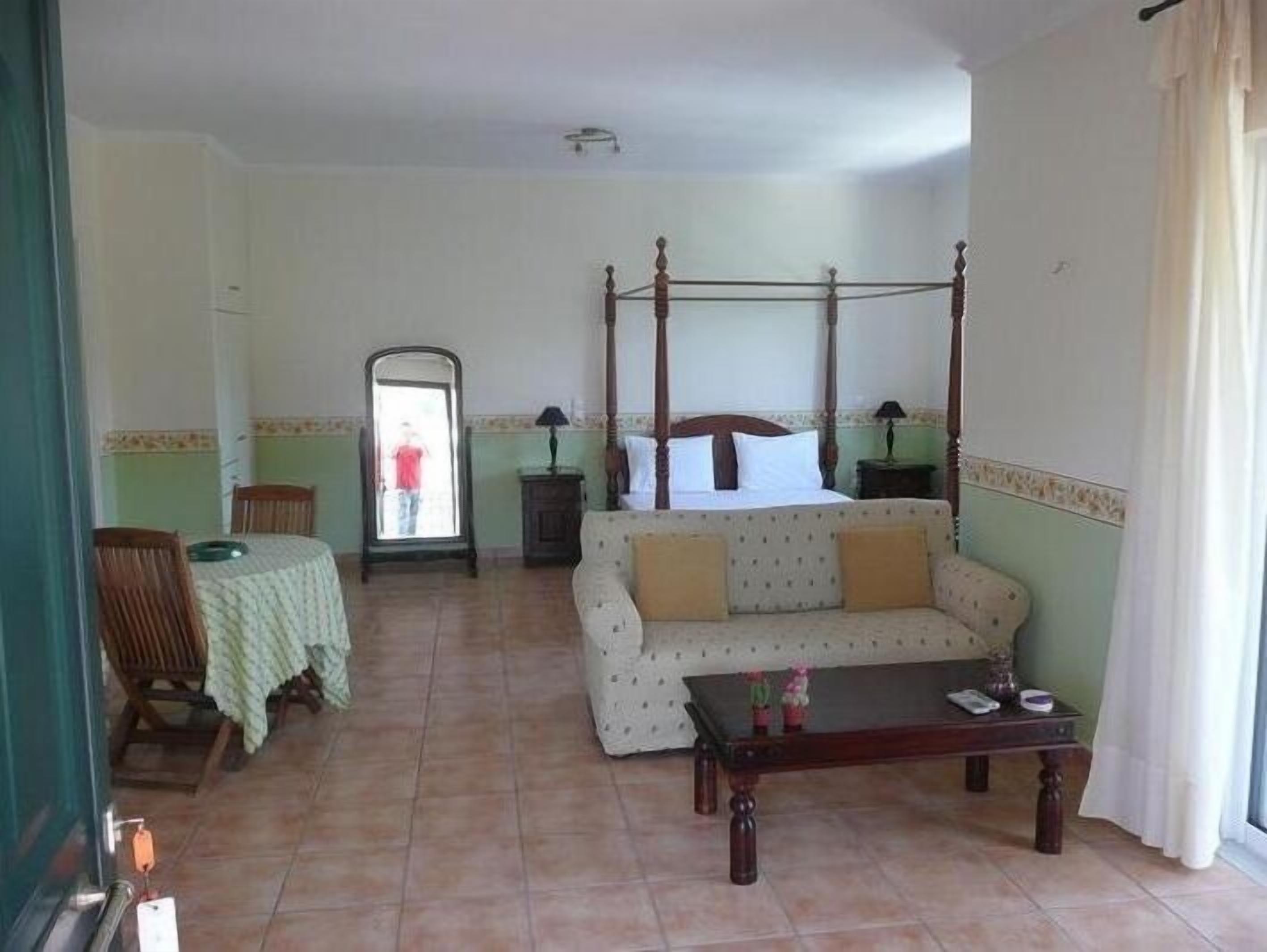A room with a four-poster bed, a sofa, a small table, and a mirror.