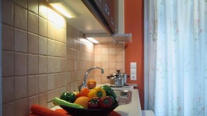 A kitchen with a sink, a bowl of fruit, and a rolled-up towel on the counter. - Anthias Garden (Lefkada)