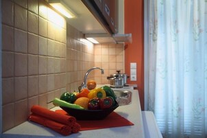 Una cocina con un lavamanos, un cuenco de fruta y una toalla enrollada sobre la encimera.
