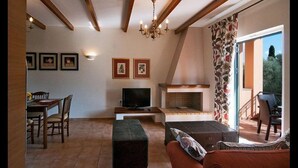 A living room with a fireplace, a television, and a dining area with chairs and a table. - Anthias Garden (Lefkada)