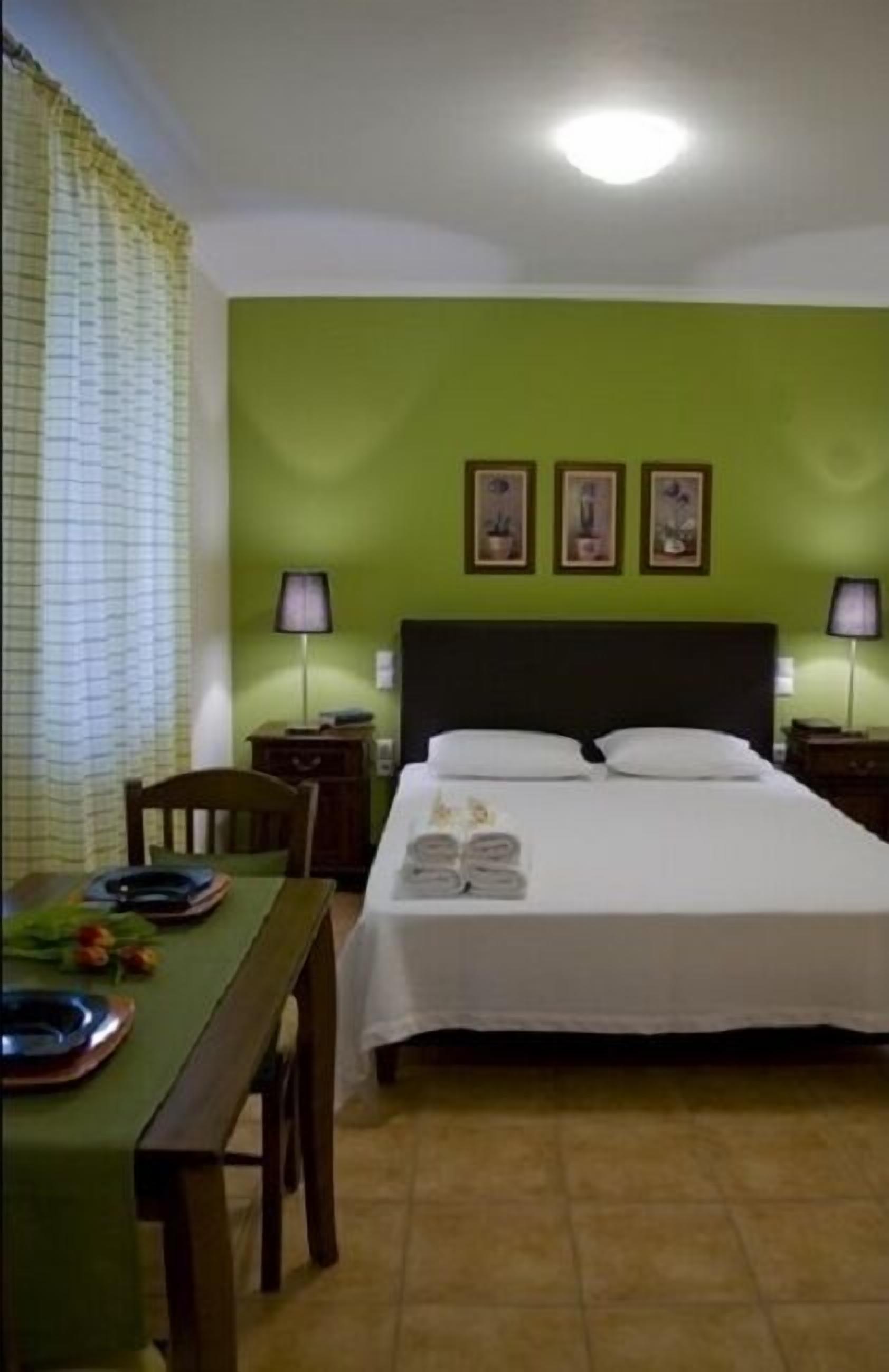 A hotel room with a bed, two bedside tables, a desk, and a chair.