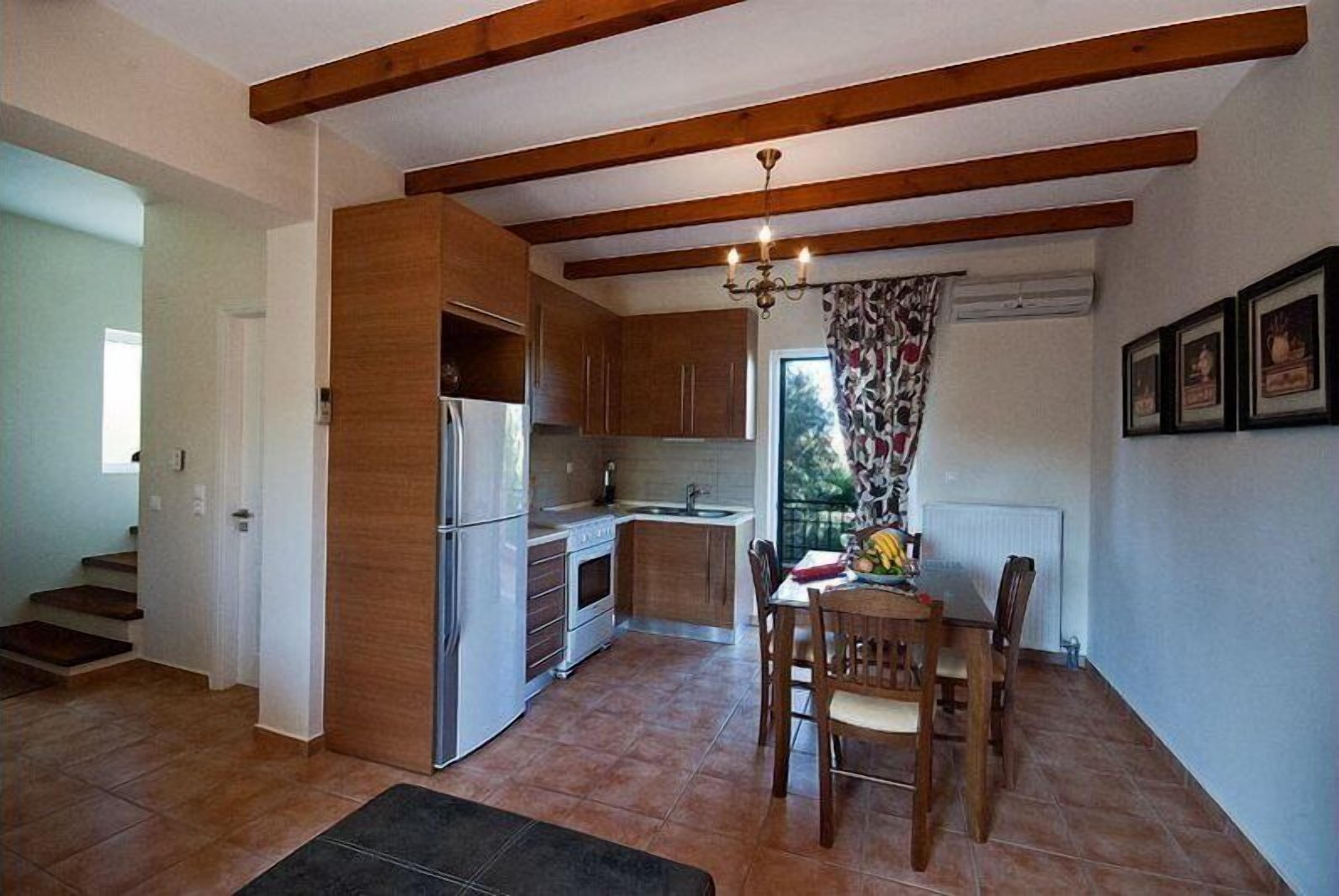 Una cocina compacta con armarios de madera, horno empotrado y comedor con mesa y sillas.