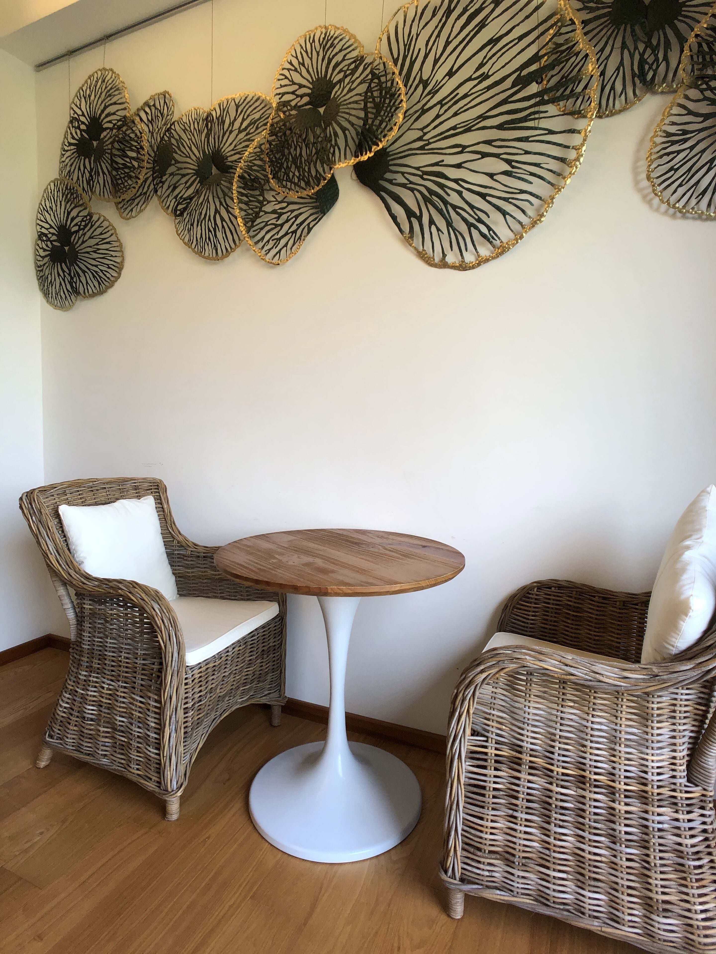 Una stanza con sedie in vimini, un tavolo rotondo in legno e decorazioni alle pareti.