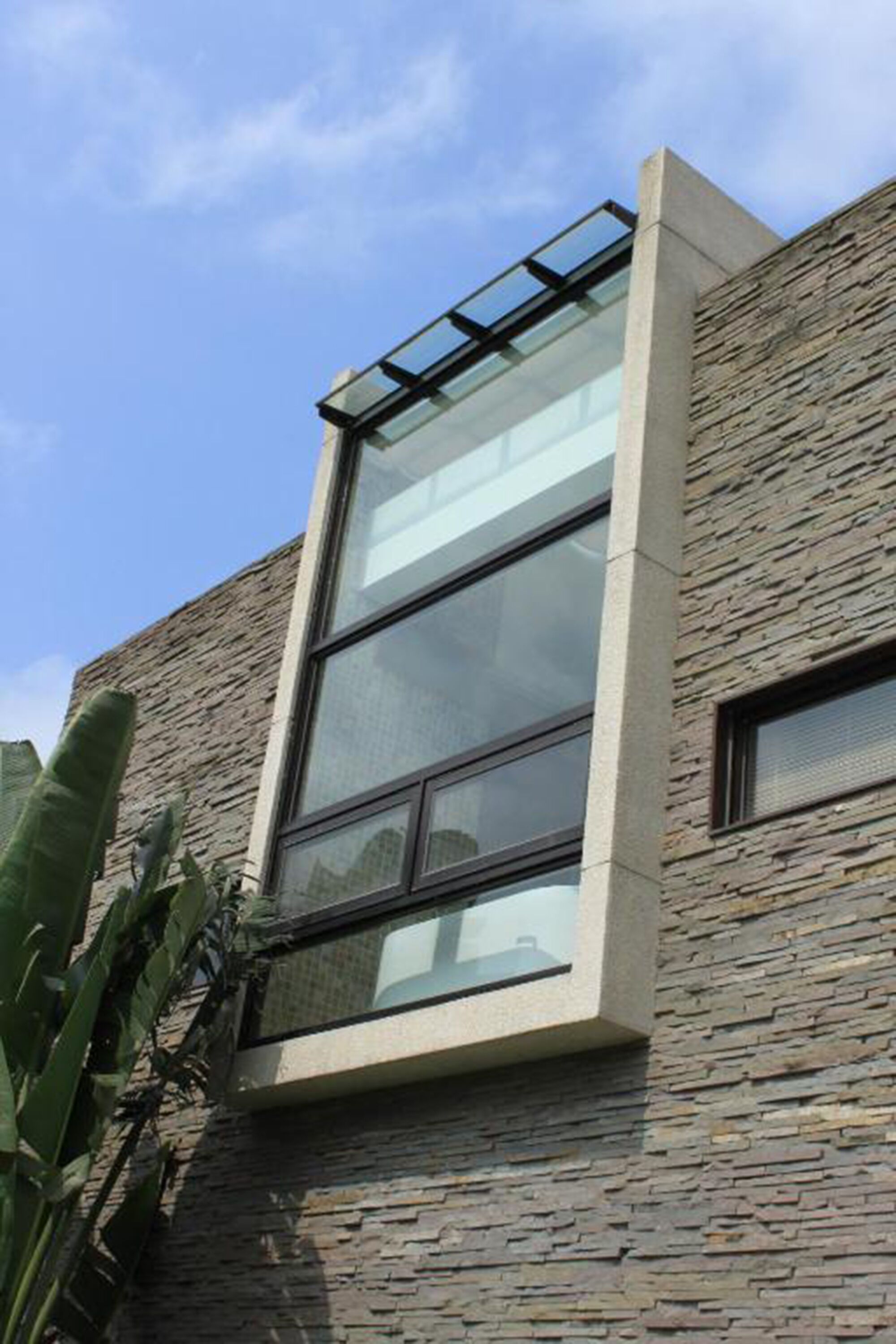 Un edificio moderno con un amplio ventanal y fachada de piedra.