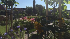A garden with various flowers and a wooden pergola structure. - Hotel Valkenhof (Zoutelande)