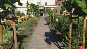 A garden pathway leading to a building with a white facade and red-tiled roof. - Hotel Valkenhof (Zoutelande)