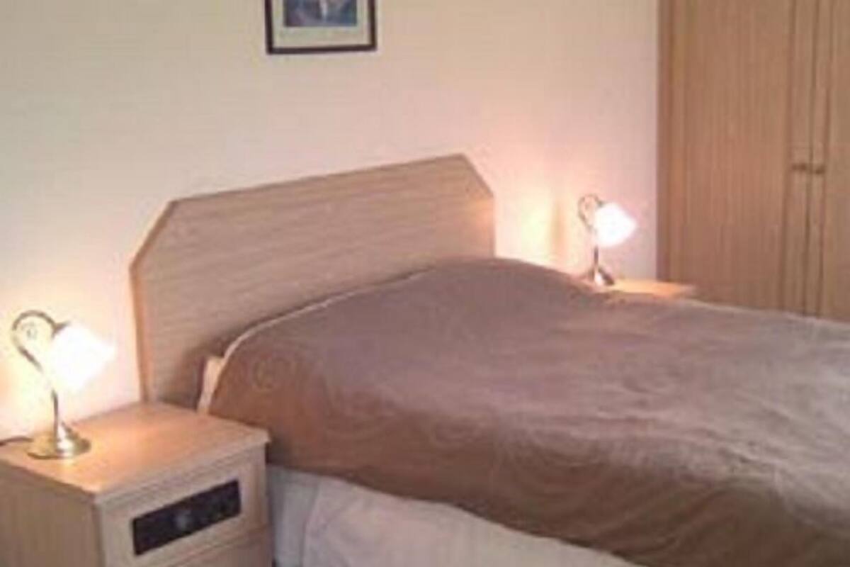 A bedroom with a bed, nightstand, and a wardrobe.