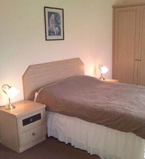 Quarto com cama, mesa de cabeceira e guarda-roupa.