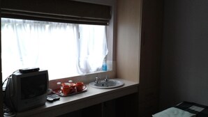 A small kitchenette with a window, a sink, and a television. - Overnight Stays Stockport (Stockport)
