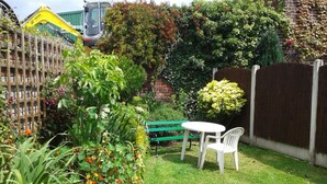 A small, enclosed garden with a wooden fence, a bench, and a table. - Overnight Stays Stockport (Stockport)