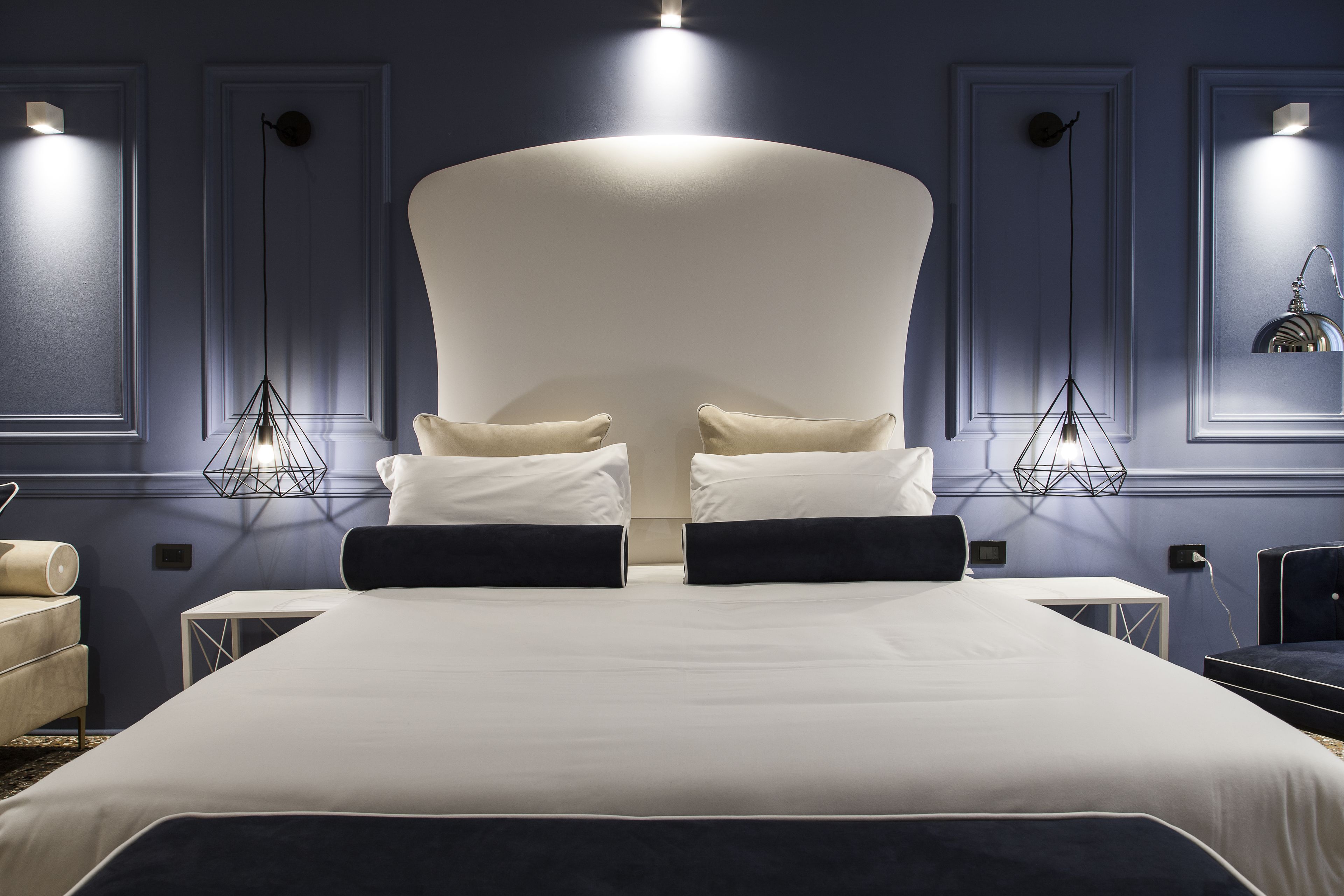 Una habitación de hotel moderna con una cama grande, dos mesitas de noche y una mesita auxiliar.