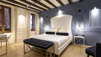 A modern bedroom with a large bed, bedside tables, a bench, and a desk.