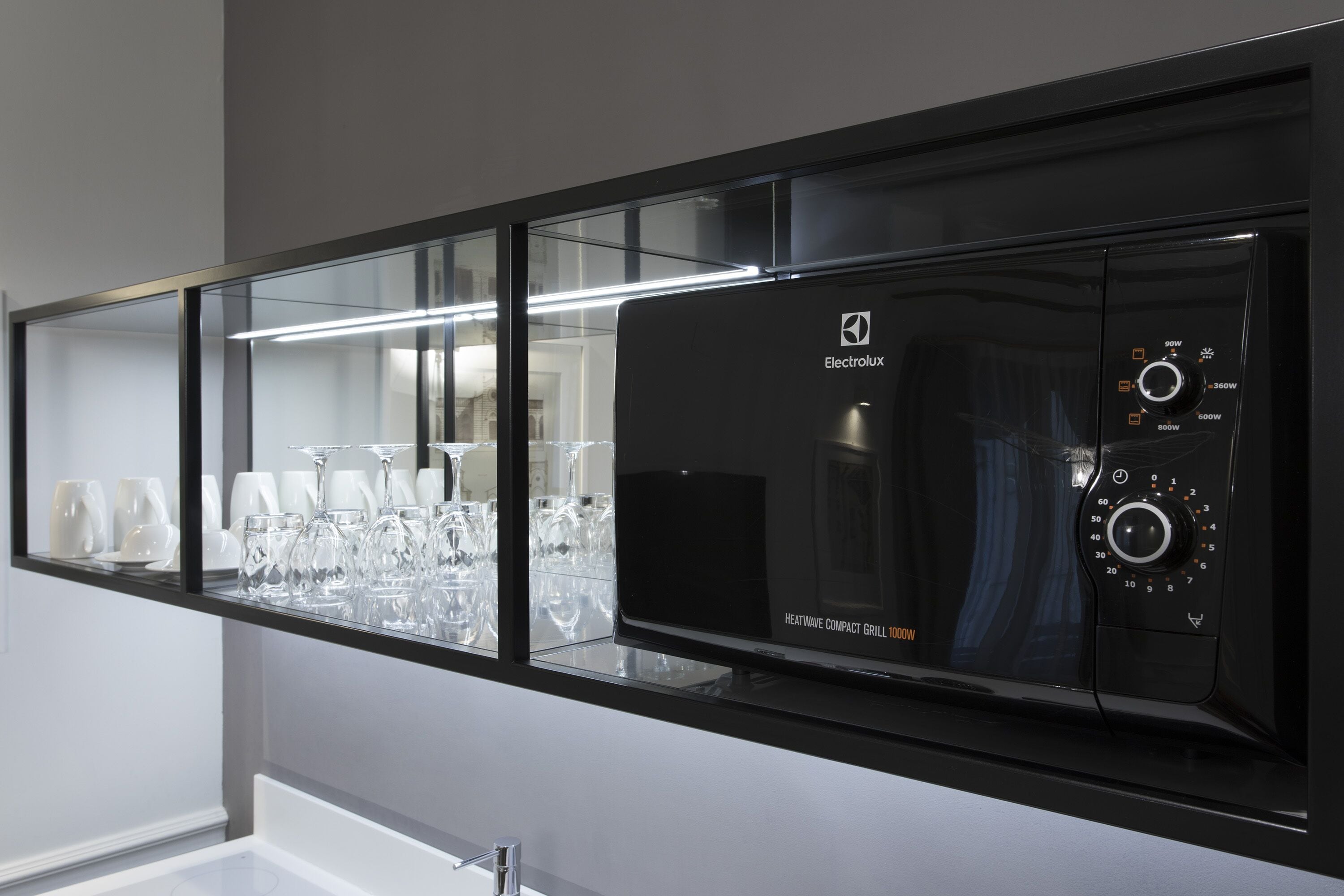 Un horno microondas Electrolux negro con panel de control digital, sobre una encimera blanca.