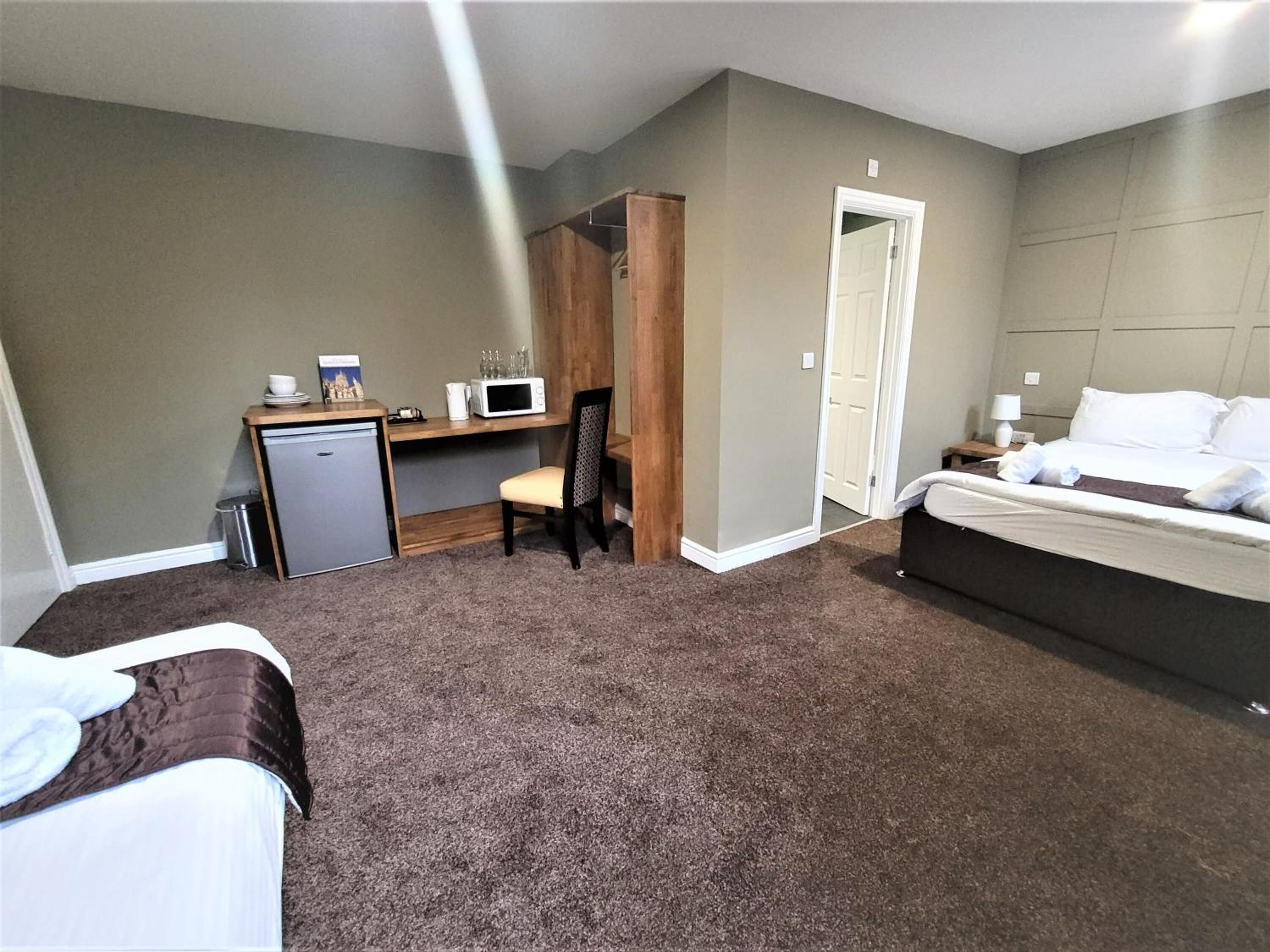 A hotel room with a bed, a desk with a chair, a microwave, and a small refrigerator.