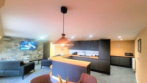 A modern kitchen with dark cabinets, a central island, and a stone accent wall. - The New County Hotel (Gloucester)