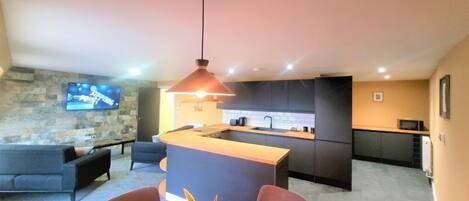 A modern kitchen with dark cabinets, a central island, and a stone accent wall.
