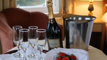 A table with a bottle of Prosecco, four empty wine glasses, a metal bucket, and a bowl of strawberries.