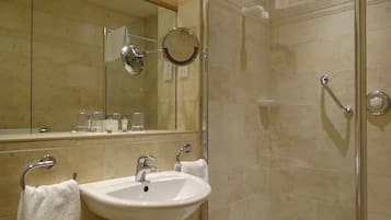 A bathroom with a sink, mirror, and shower.