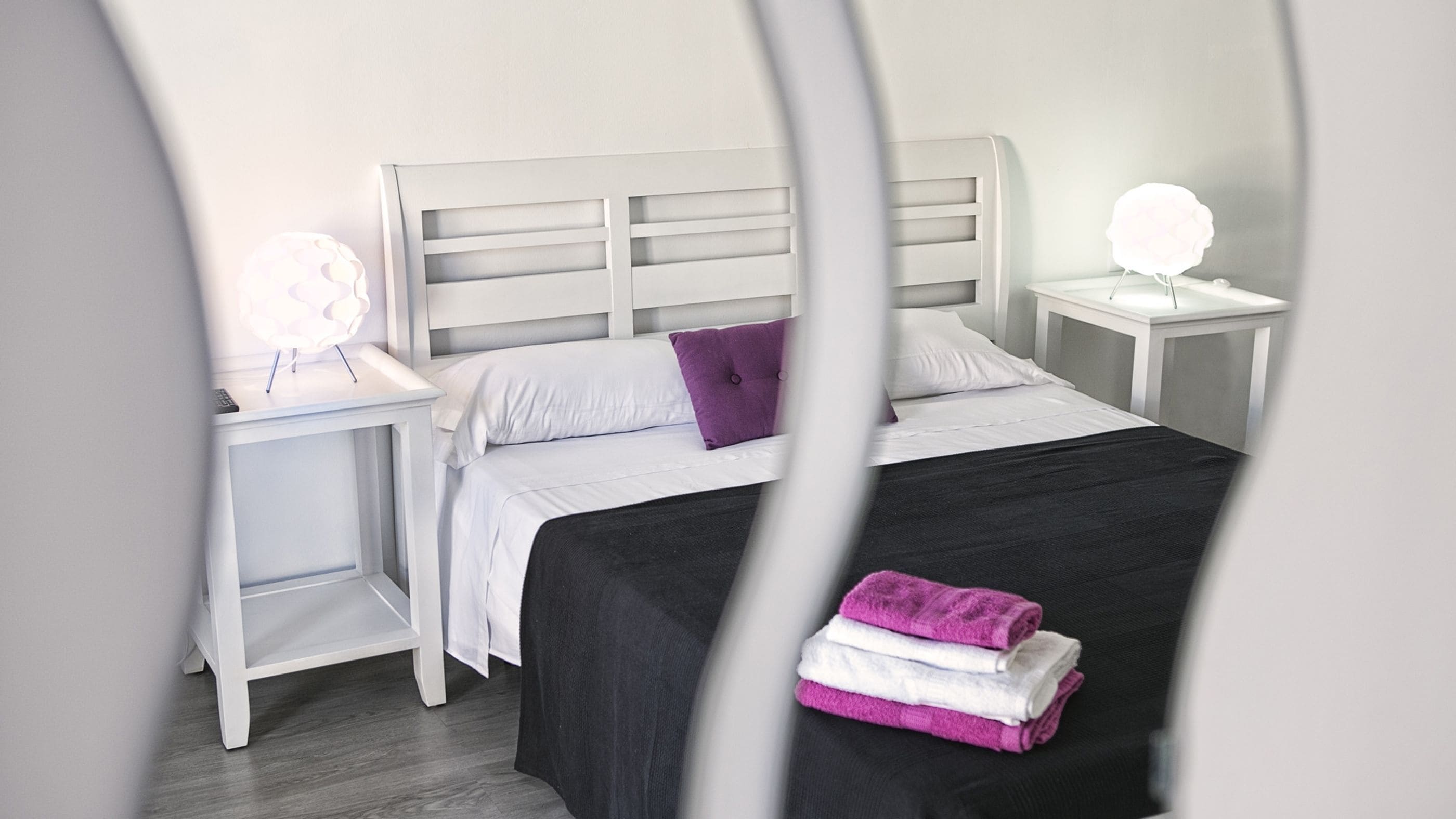 Un dormitorio ordenado con una cama, dos mesitas de noche y una mesilla.