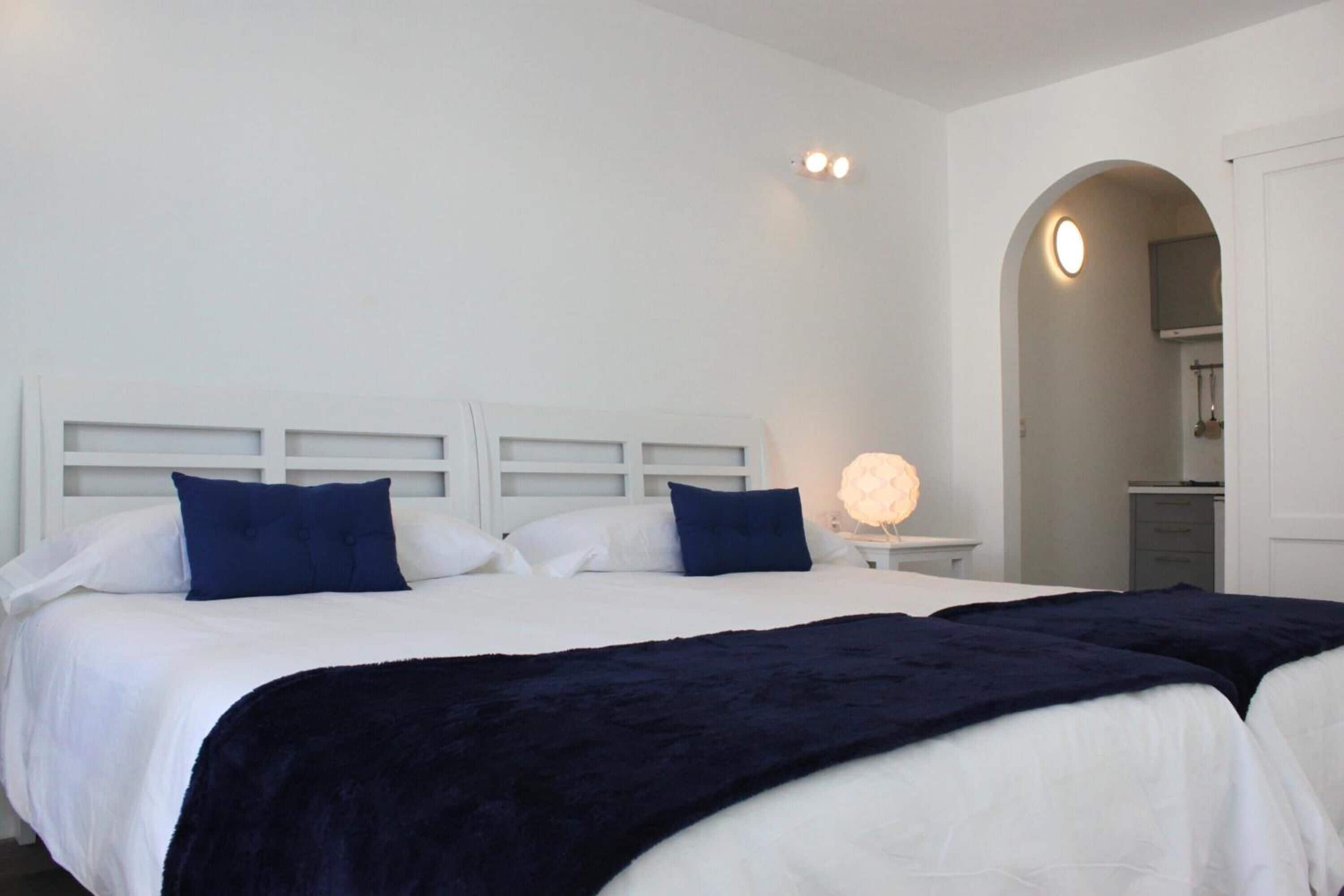 A bedroom with two beds, white headboards, and a bedside lamp.