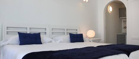 A bedroom with two beds, white headboards, and a bedside lamp.