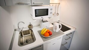 A modern kitchen with a microwave, toaster, kettle, and a sink. - Corralejo Lodge (La Oliva)