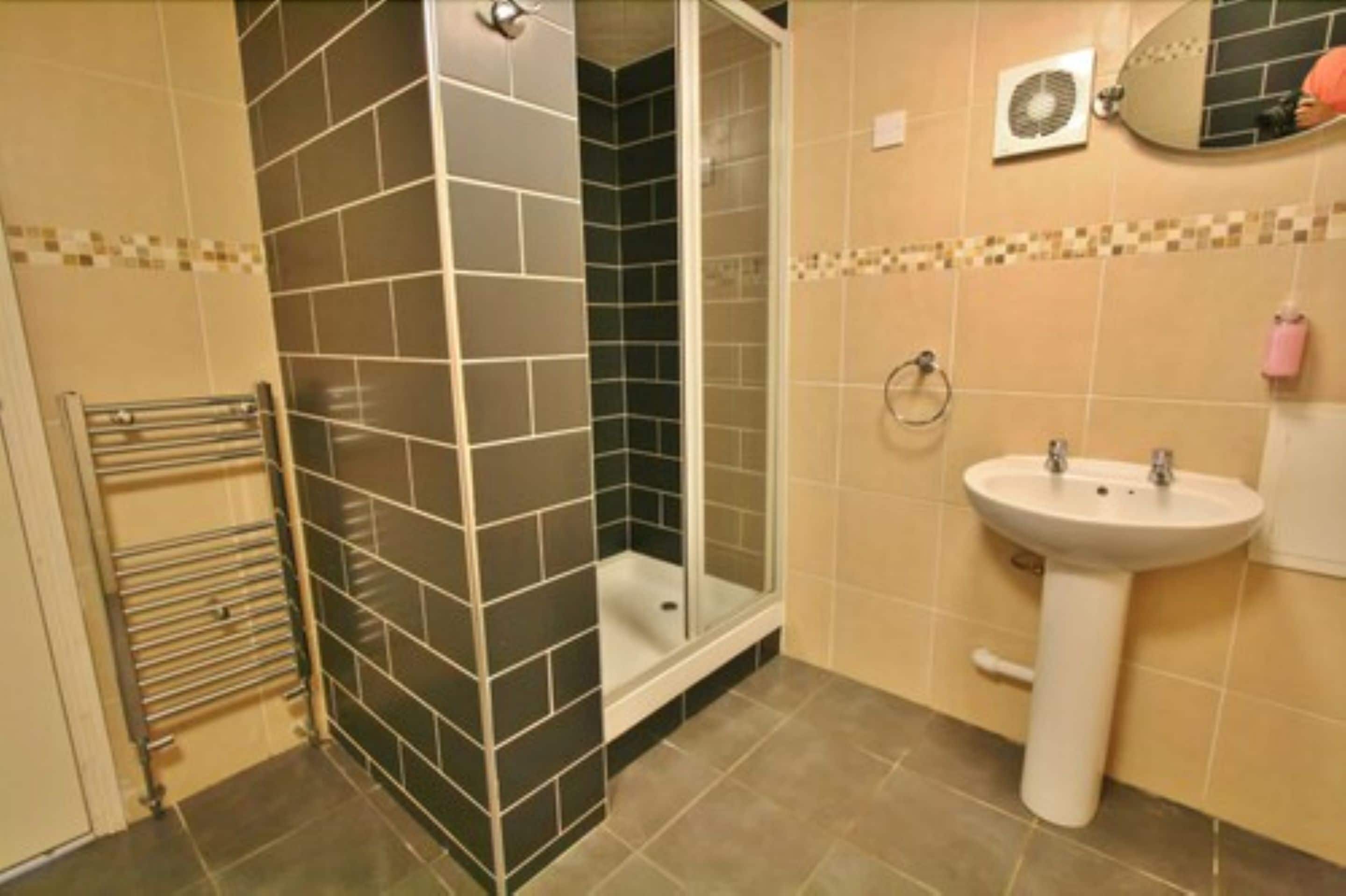 Ein Badezimmer mit Dusche, Waschbecken und Handtuchhalter.