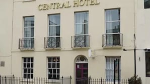 Un bâtiment portant l’inscription « CENTRAL HOTEL », avec une façade symétrique, de nombreuses fenêtres et une entrée centrale dotée d’une porte.