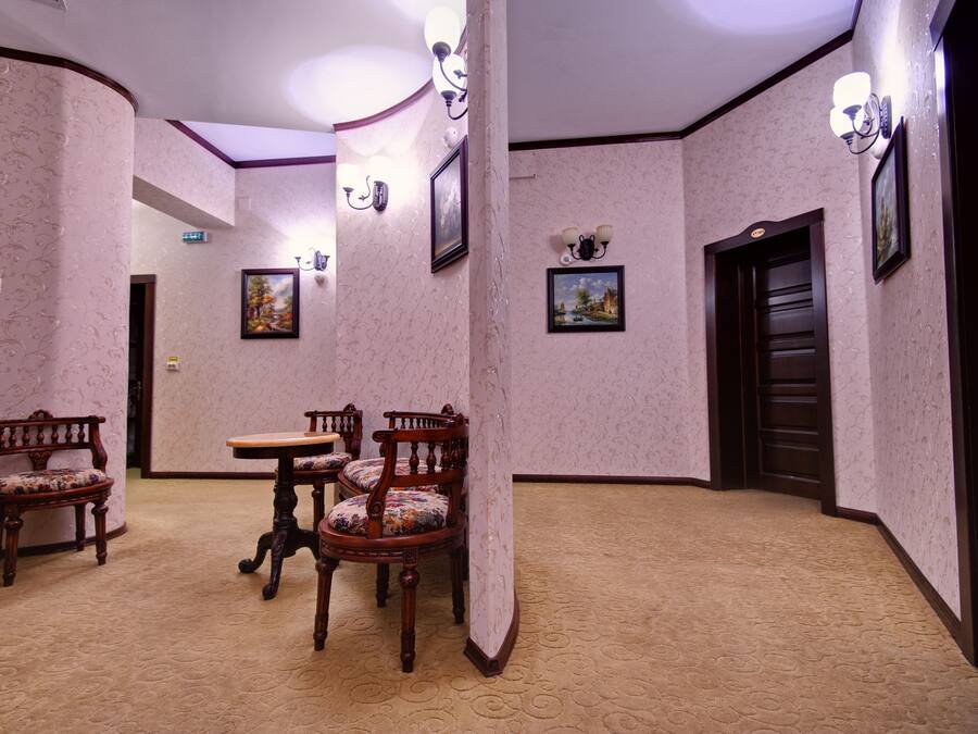 A room with patterned wallpaper, a round table with chairs, and a door.