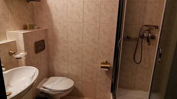 Een badkamer met douche, toilet, wastafel en handdoekhouder.
