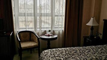 Una habitación de hotel con una cama grande, una silla, una mesita y una lámpara.