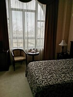 Una habitación de hotel con una cama grande, una silla, una mesita y una lámpara.