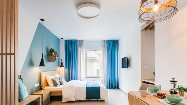 Un dormitorio moderno con cama, mesitas de noche, un escritorio y una ventana con cortinas.