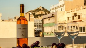 Una mesa con una botella de vino, dos copas de vino y un cuenco de fruta.