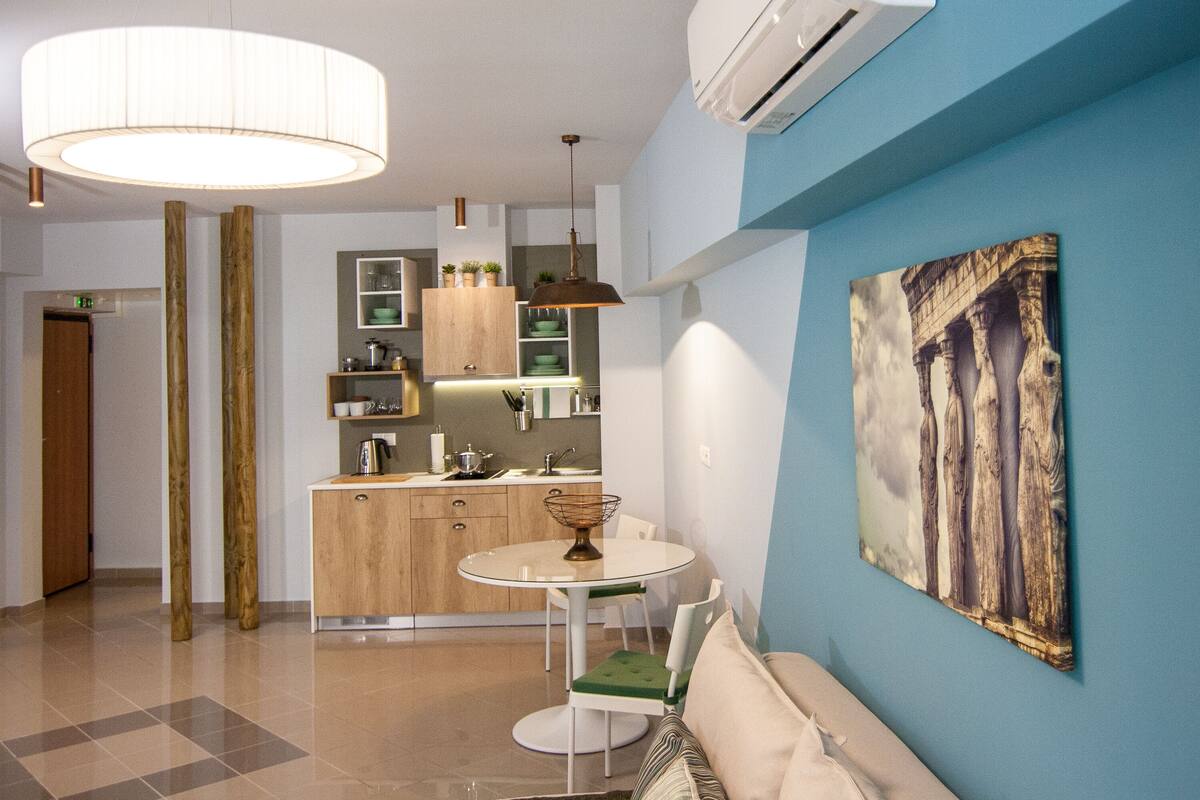 A modern kitchen with a round dining table, a sofa, and a large painting on the wall.