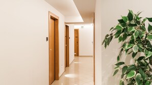 Un pasillo con puertas de madera, piso de baldosas y una planta en maceta.