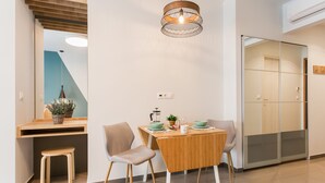 Una cocina moderna con una mesa de comedor de madera, dos sillas, una lámpara colgante y un taburete pequeño.