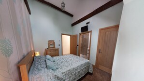 Une chambre à coucher comprenant un lit, une armoire en bois et une porte donnant sur une salle de bain.