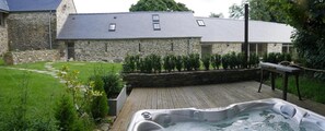 A stone building with a sloped roof, a hot tub, and a wooden deck. - Rhostwarch Bed and Breakfast (Crymych)