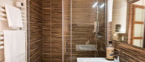 A modern bathroom with a glass shower enclosure, a white sink, and a mirror.